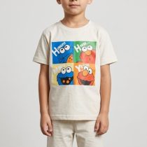 Young boy model wearing a cream-colored kids Sesame Street t-shirt and shorts co-ord set featuring Elmo and Cookie Monster graphics in a studio setting.