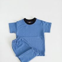 A blue short-sleeved t-shirt and matching shorts set made from textured popcorn fabric, featuring a black collar.