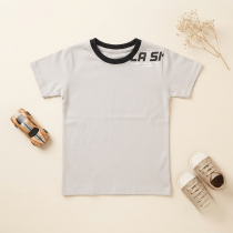 Light grey and black boys' T-shirt flatlay, styled with a small retro wooden toy car, baby shoes, and dried flowers on a light wood background