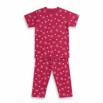 A professional studio flat-lay photograph of a magenta-colored kids' short-sleeve t-shirt and matching pajama pants featuring a white bow and heart pattern, displayed on a clean white background.