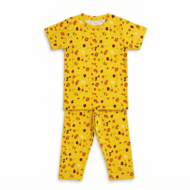 A high-quality flat-lay product photo of a yellow kids' t-shirt and pajama pants with a colorful floral print, displayed on a clean white background.