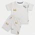 A professional product photograph of a folded kids' matching co-ord set, including a t-shirt and shorts with a geometric and safari animal print, laid flat against a clean, neutral off-white background.