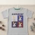 A light grey toddler t-shirt with a four-panel pop-art bunny graphic and text, hanging and decorated with miniature Christmas trees and pinecones on a neutral background.